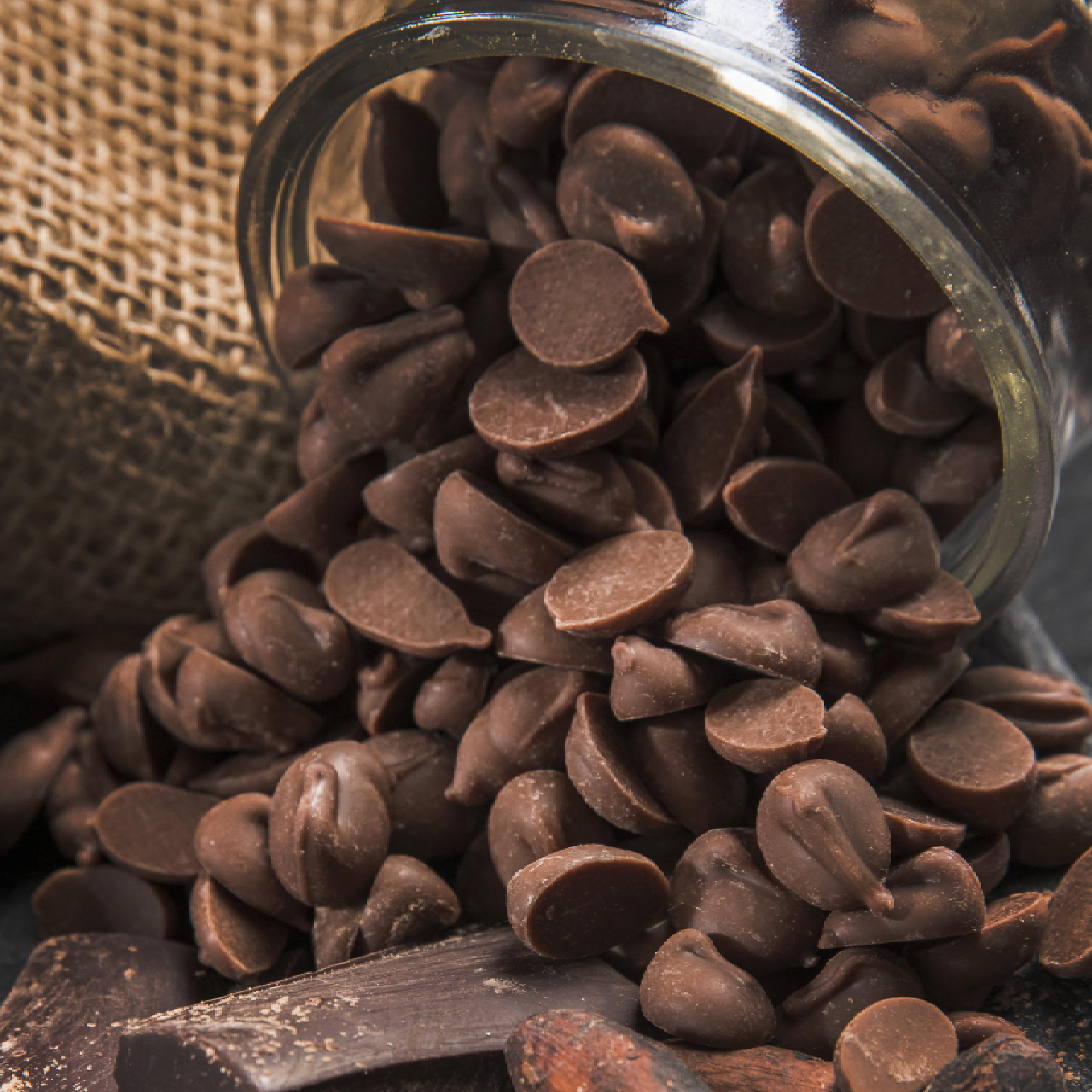 The image depicts the spilling of chocolate chips from a glass container