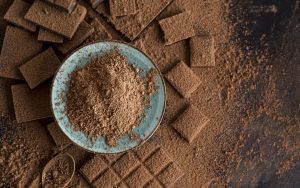 The image features a plate full of chocolate powder with numerous squares of chocolate surrounding it.
