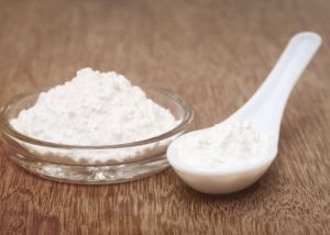 The image features a bowl of kulfi stabilizer accompanied by a spoon. The setting appears to be an indoor kitchen environment, reflecting typical culinary preparations.
